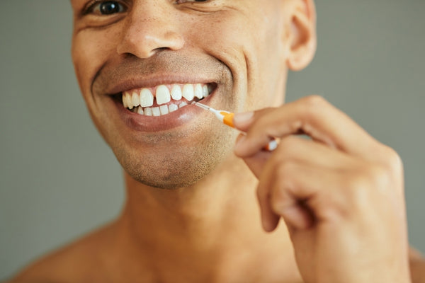 Man uses an interdental brush to clean places where his toothbrush cannot reach