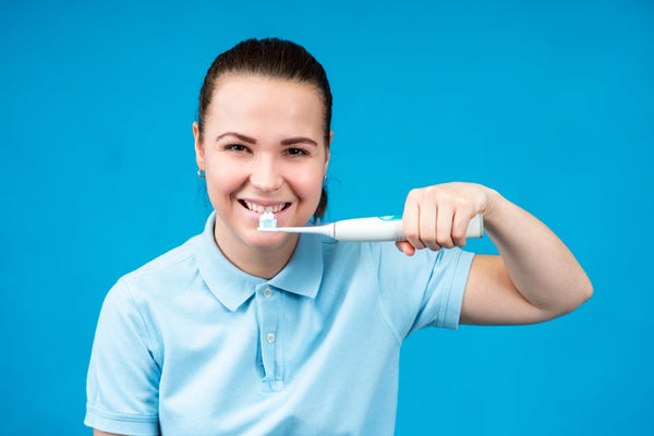 Woman brushes her teeth using an electric toothbrush