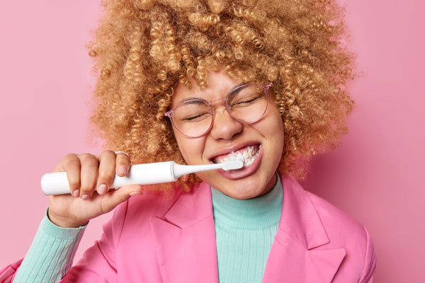 Woman brushes her teeth using an electric toothbrush